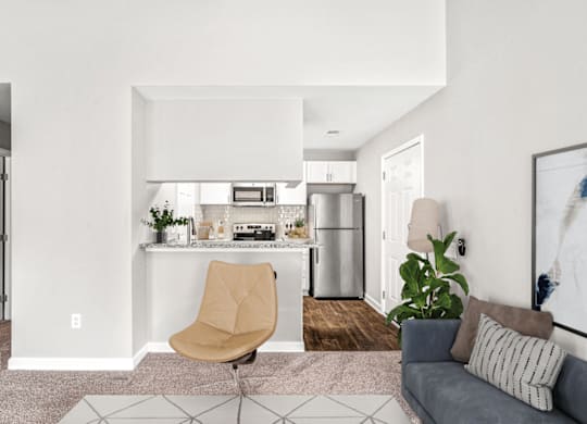 A modern kitchen with a beige chair and a grey couch at Paces Pointe Apartment Homes, North Carolina