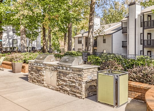 A stone wall with a metal gate in front of a building at Paces Pointe Apartment Homes, North Carolina, 28105