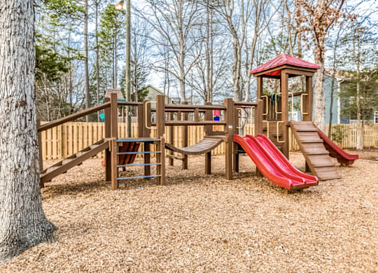 A playground with a red slide and a wooden structure at Paces Pointe Apartment Homes, Matthews