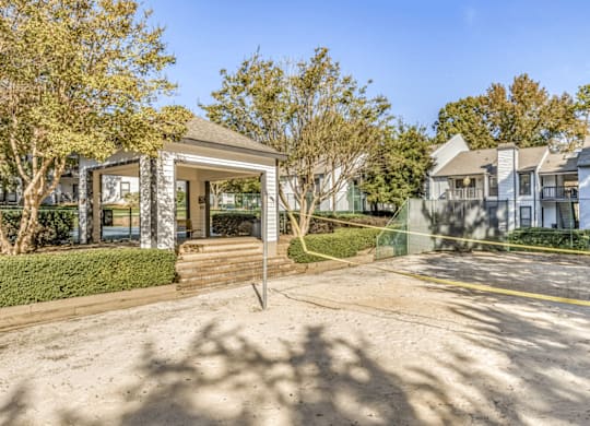 A building with a glass door and windows is surrounded by trees and a clear sky at Paces Pointe Apartment Homes, Matthews, 28105