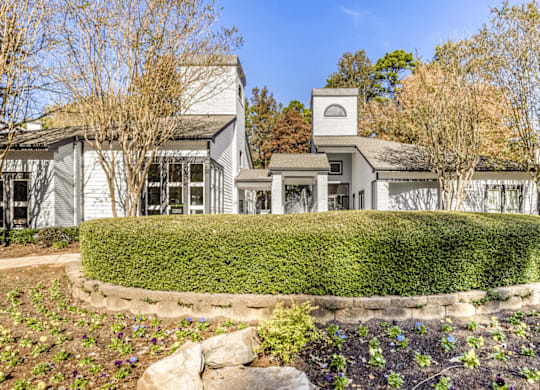 A white house with a grey roof and a small tower is surrounded by a well-manicured garden at Paces Pointe Apartment Homes, North Carolina
