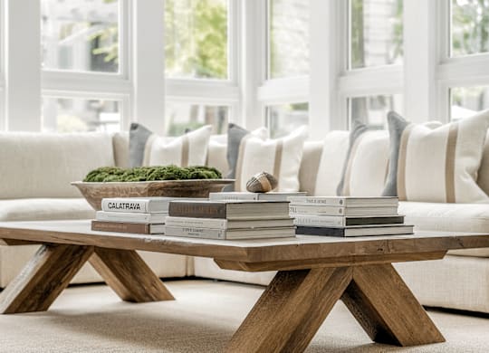 A coffee table with a stack of books on top of it in front of a white couch at Paces Pointe Apartment Homes, North Carolina, 28105
