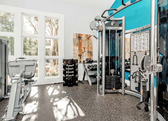 A gym with a variety of equipment including a treadmill, weights, and a bench press at Paces Pointe Apartment Homes, Matthews, North Carolina