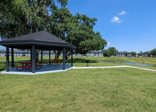 A gazebo with red benches is surrounded by a grassy area.