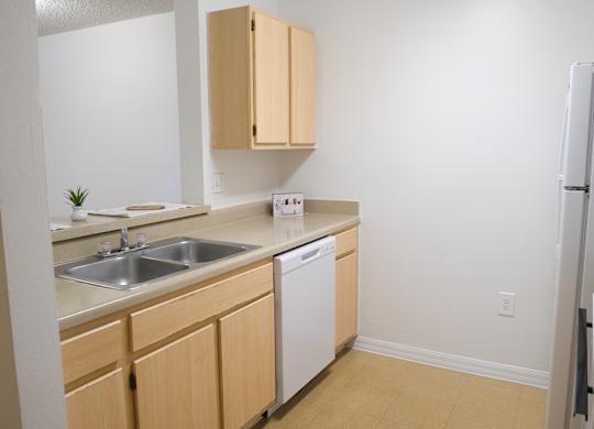 A kitchen with a white dishwasher and wooden cabinets.