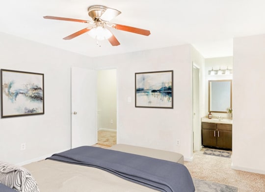 A bedroom with a bed, a ceiling fan, and two framed pictures on the wall at Regency Park Apartment Homes, Raleigh, 27616