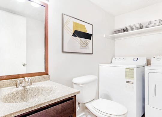 A bathroom with a toilet, sink, and a picture on the wall at Regency Park Apartment Homes, North Carolina, 27616