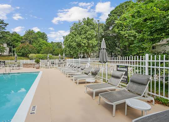 A pool area with sun loungers and a warning sign at Regency Park Apartment Homes, Raleigh, NC