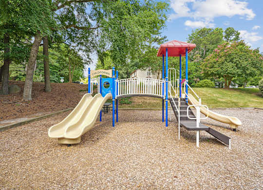 A playground with a yellow slide and a blue and white structure at Regency Park Apartment Homes, Raleigh, NC, 27616