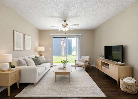 A living room with a white couch, a wooden coffee table, a flat screen TV, and a ceiling fan.