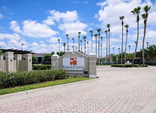 The Sabal Chase sign is in front of a row of palm trees.