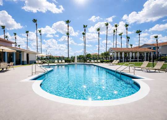 A large outdoor swimming pool surrounded by palm trees and lounge chairs.