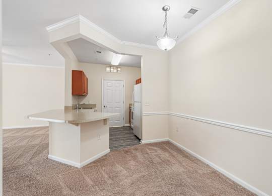 A room with a kitchenette and a doorway leading to another room.