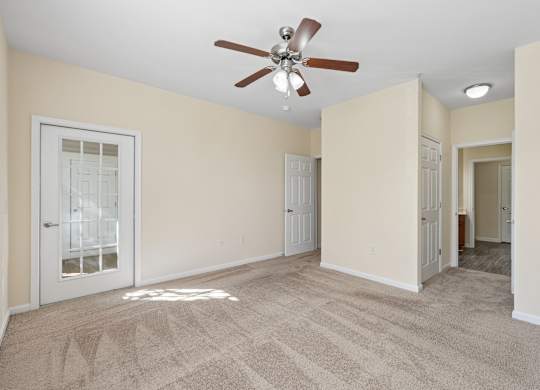 A room with a ceiling fan and carpeted floor.
