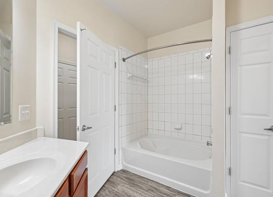 A white bathroom with a tub, sink, and shower.