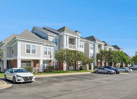 A row of townhouses with cars parked in front.