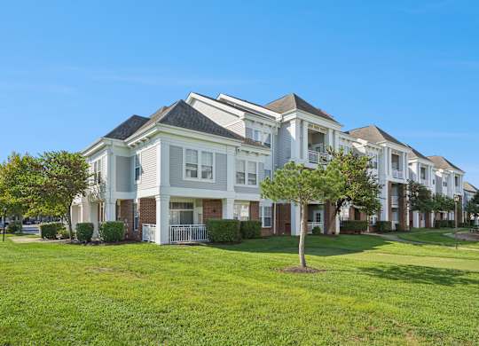 A row of white houses with green lawns in front.