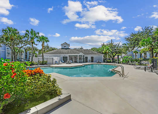 Pool area with tanning chairs on the deck surrounded by natural landscaping