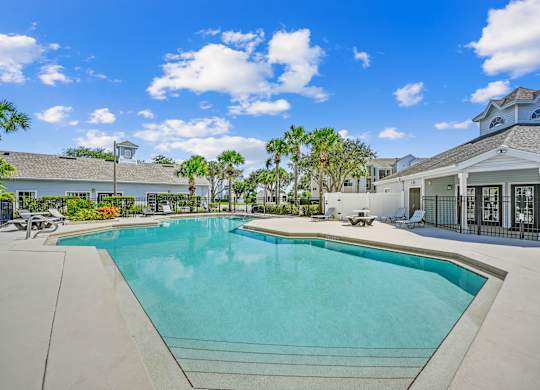 Pool area with tanning chairs on the deck surrounded by natural landscaping