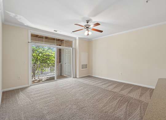 A room with a carpeted floor and a ceiling fan.
