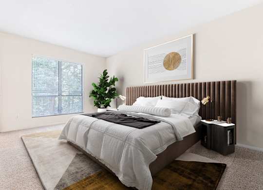 A bedroom with a large bed and a small tree.