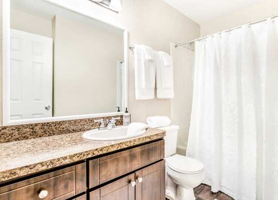 A white bathroom with a toilet, sink, and shower.