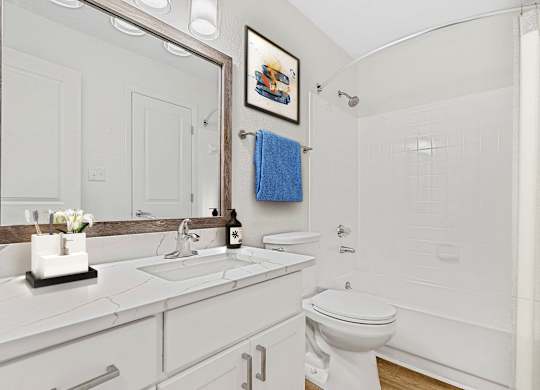 A white bathroom with a blue towel hanging on the towel rack.