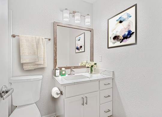 A white bathroom with a towel hanging on the towel rack.