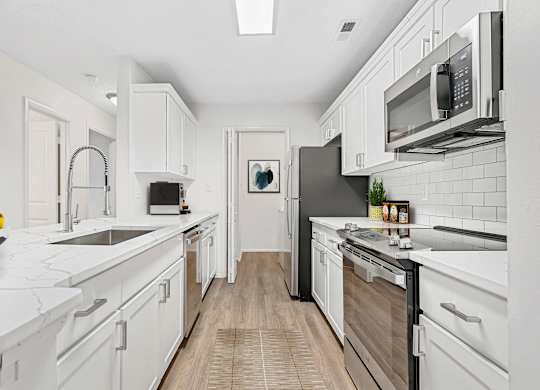 A modern kitchen with white cabinets and a black refrigerator.