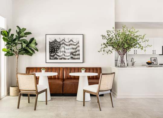 A living room with a brown couch, two chairs, and a table with a vase of flowers on it.