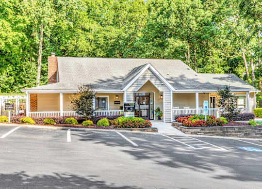 A small building with a porch and a parking lot in front.