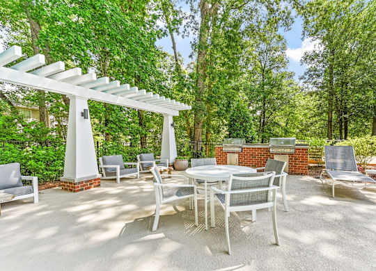 A patio with a table and chairs under a white pergola.
