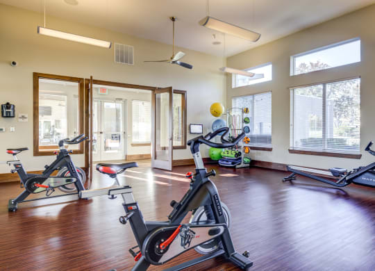 a gym with treadmills and exercise equipment in a room with windows