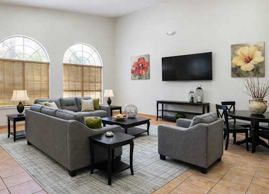 A living room with a grey couch, a black coffee table, and a flat screen TV mounted on the wall.