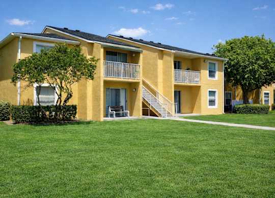 A yellow apartment building with a green lawn in front.