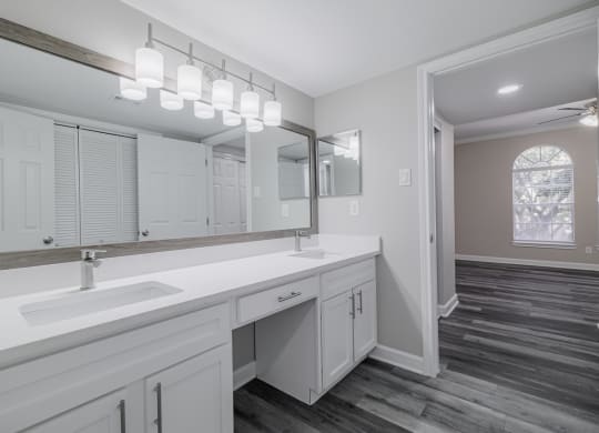 bathroom with dual vanities, white countertops and cabinetry