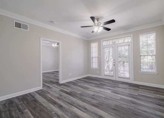 an empty living room with a ceiling fan and windows