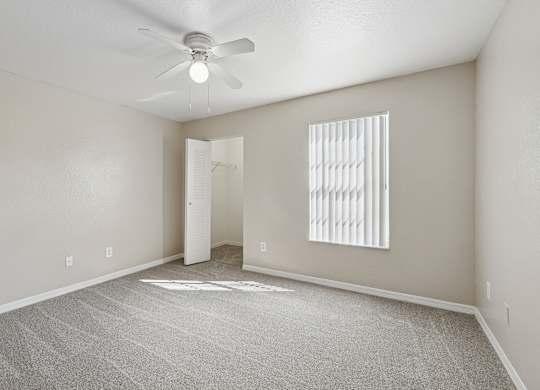 A room with a ceiling fan and a window with blinds.
