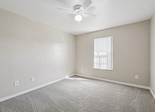A room with a ceiling fan and a window with blinds.