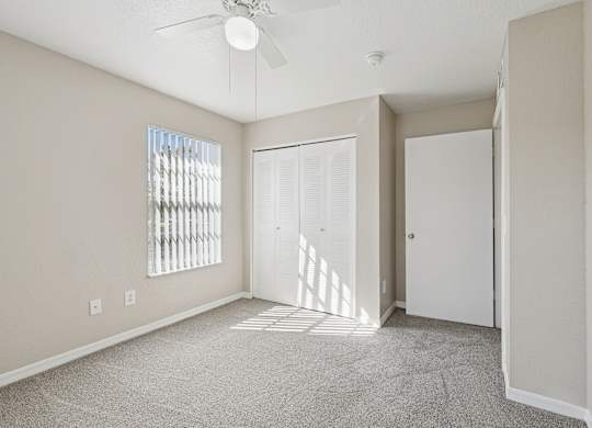 A room with a ceiling fan and a window with blinds.