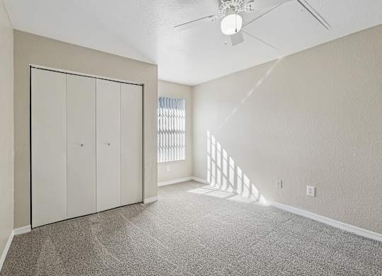 A room with a ceiling fan and a window with blinds.