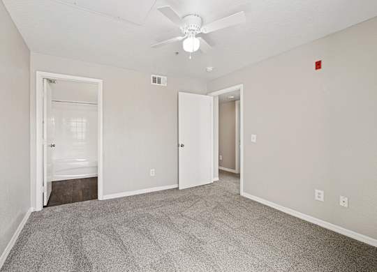 A room with a carpeted floor and a ceiling fan.