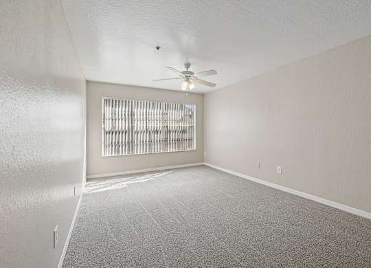 A room with a ceiling fan and a window with blinds.