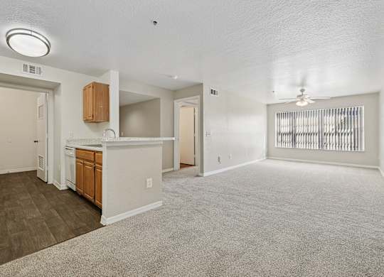 A spacious living room with a carpeted floor and a ceiling fan.