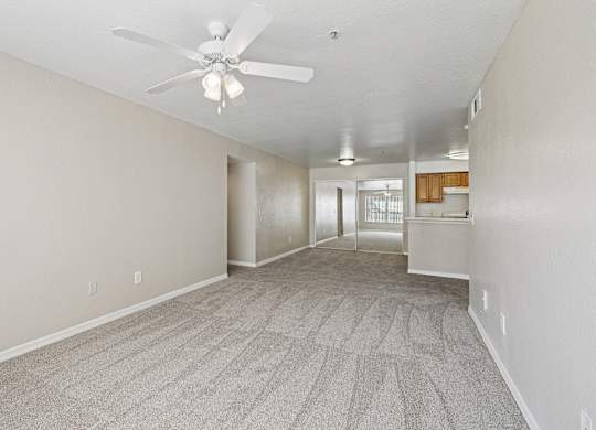 A room with a ceiling fan and carpeted floor.