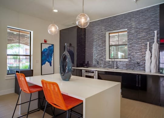 clubhouse kitchen with black cabinets and a white table with orange chairs