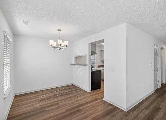 A white room with wood flooring and a chandelier.