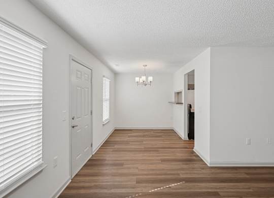 A long, empty hallway with white walls and wood flooring.