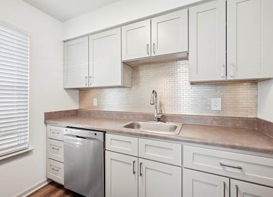A kitchen with white cabinets and a tiled backsplash.