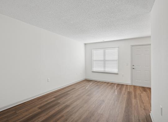 A room with wooden flooring and a window with blinds.